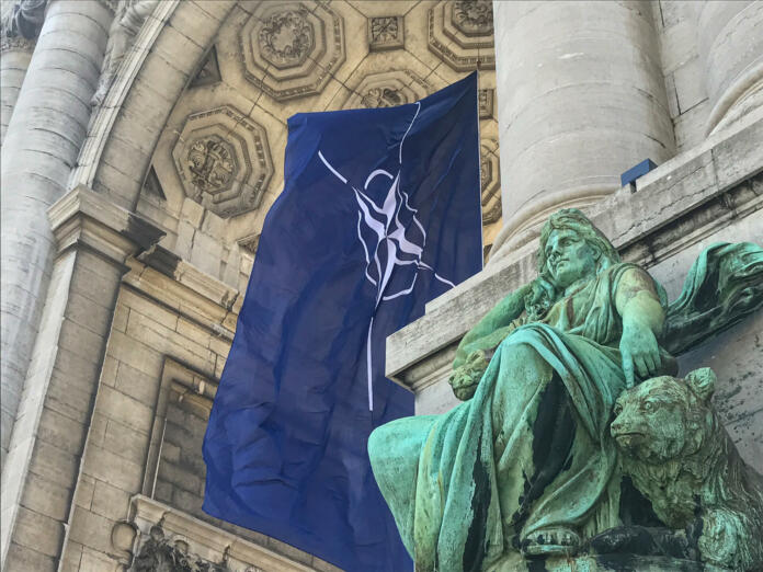 BRUSSELS, BELGIUM - JUNE 14, 2021: NATO flag fluttering in the wind in the arcades of the Cinquantenaire in Brussels