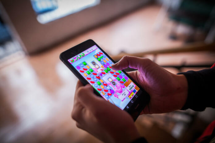 Bucharest, Romania - January 25, 2017: Close up illustrative editorial shot of a person's hands, holding a smartphone and playing Candy Crush Saga game.