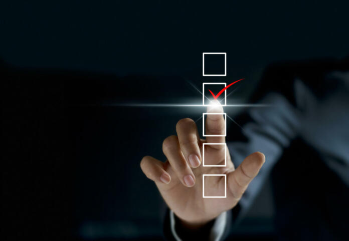 businessman checking mark on checklist with a red marker on dark background