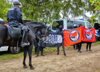 Kaj sploh je Antifa? Celle, Germany, September 26, 2020: Policeman on a black horse stands in front of demonstrators carrying banners of Antifa