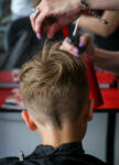Close-up of a female hairdresser's hands cutting child's hair using scissors and comb