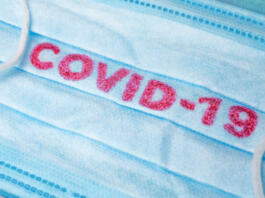 Covid-19 - Wuhan Novel Coronavirus pneumonia gets official name from WHO: COVID-19. Disposable dressing on the face. Healthcare background. Blue medical disposable face mask with covid-19 print