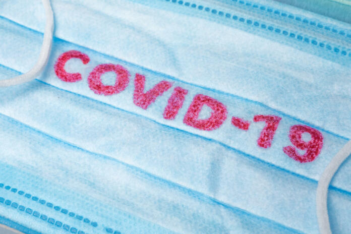Covid-19 - Wuhan Novel Coronavirus pneumonia gets official name from WHO: COVID-19. Disposable dressing on the face. Healthcare background. Blue medical disposable face mask with covid-19 print