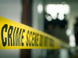 crime concept by police line tape with blurred forensic law enforcement background in cinematic tone and copy space