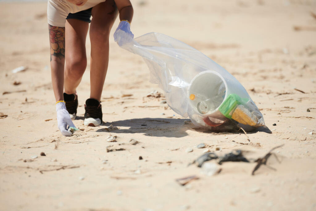 Cropped image of female volunteer cleaning beach from plastic waste