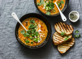 Piščančji žur Curried red lentil tomato and coconut soup - delicious vegetarian food on grey background, top view. Flat lay served healthy lunch