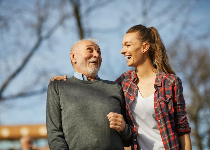 Daughter, or granddaughter or nurse caregiver with senior man with a walking cane stick and wheelchair outdoors