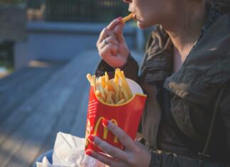 Kako te restavracije s hitro hrano prelisičijo, da zapraviš več? Moški v rokah drži McDonald's krompirček