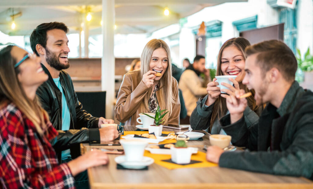 Friends group drinking cappuccino at coffee bar - People talking and having fun together at fancy cafeteria - Friendship concept with happy guys and girls at restaurant cafe - Warm bulb light filter