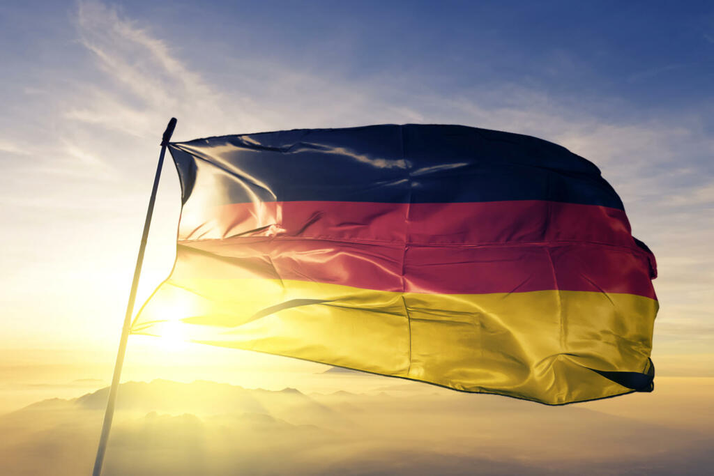 Germany German flag on flagpole textile cloth fabric waving on the top sunrise mist fog