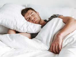 Handsome young man sleeping in bed at home