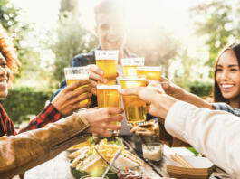 Happy friends celebrating happy hour drinking beer at brewery bar restaurant - Multi ethnic family having fun at backyard dinner party - Young people enjoying time together at open air pub