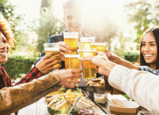 Kako se družiti brez alkohola Happy friends celebrating happy hour drinking beer at brewery bar restaurant - Multi ethnic family having fun at backyard dinner party - Young people enjoying time together at open air pub