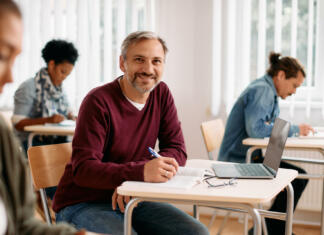Kaj se zgodi s statusom študenta po dopolnjenem 26. letu? Happy mature man attending a lecture and writing notes while looking at camera.
