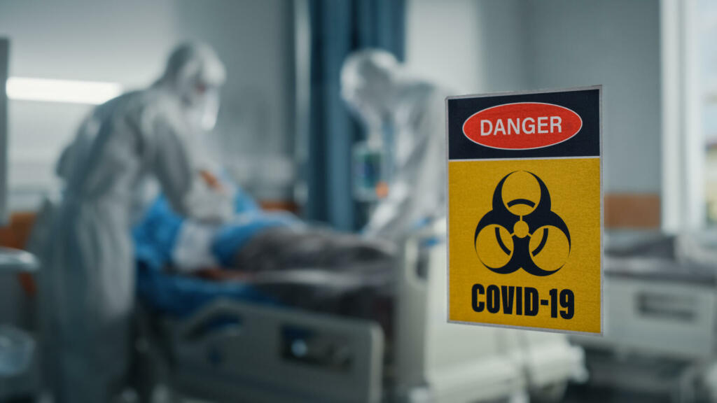 Hospital Coronavirus Emergency Department Ward: Doctors wearing Coveralls, Face Masks Treat, Cure and Save Lives of Patients. Focus on Biohazard Sign on Door, Background Blurred Out of Focus