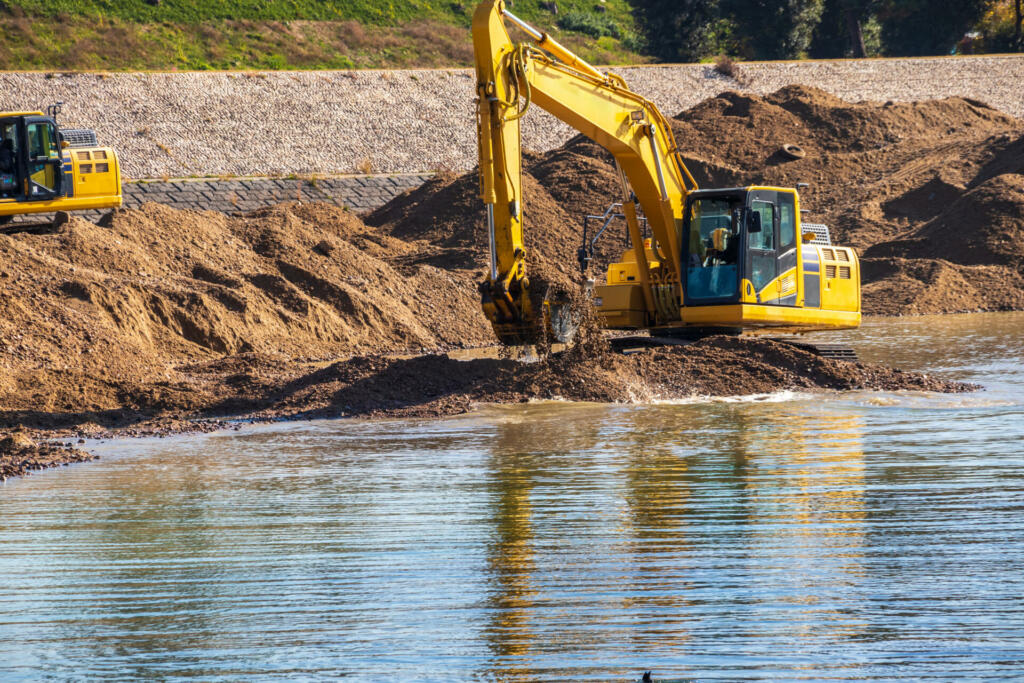 Hydraulic excavator digging up the sand in the river
