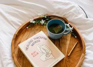Rupi Kaur izdaja novo knjigo Knjiga Healing through words na lesenem pladnju s čajem, na postelji