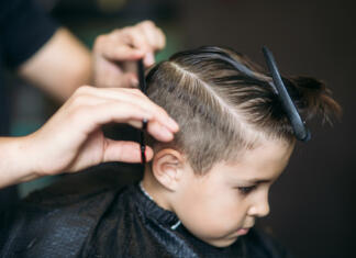 DIY frizer: kako se ostriči doma Little boy on a haircut in the barber sits on a chair.