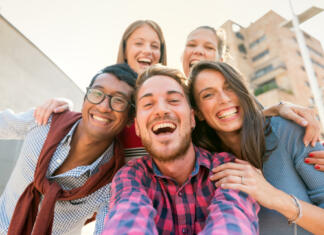 »Slovenija je za tuje študente zelo privlačna« Low angle portrait of a cheerful interracial group of five friends smiling while taking a selfie picture outdoors in the city