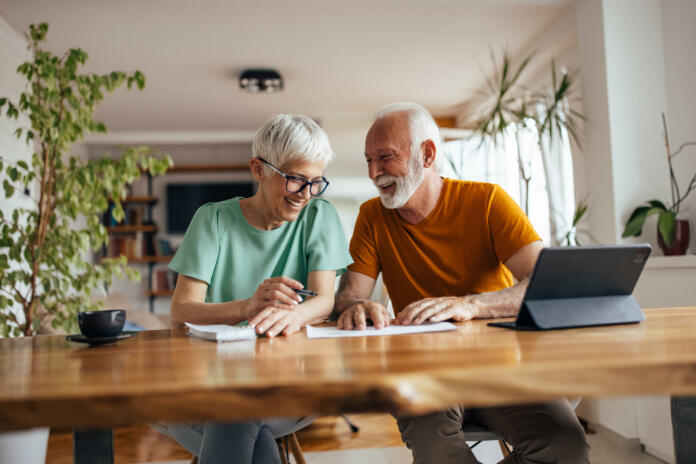 Mature husband, helping his wife with their business, at home office.