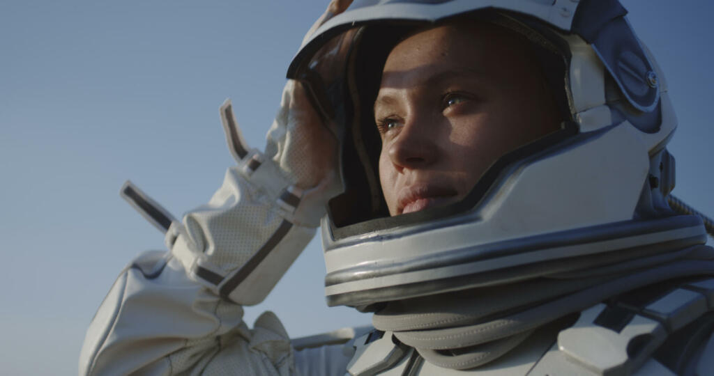 Medium shot of astronaut opening helmet and smiling