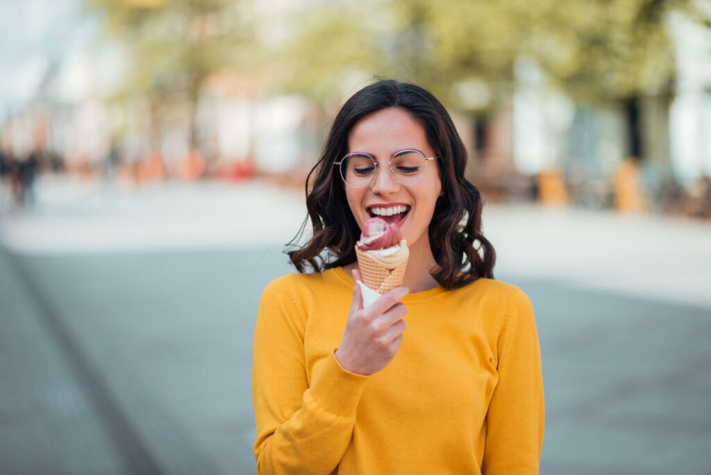 Millennial woman eating ice cream on a spring sunny day.