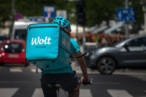 "n"nPicture of a food delivery guy from Wolt cycling in the streets of Ljubljana, Slovenia. Wolt is a Finnish technology company that is known for its food-delivery platform mobile application bought by doordash