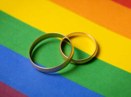 same-sex marriage concept - two wedding rings on lgbt rainbow flag
