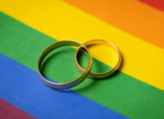 Istospolni pari lahko že zdaj prijavo sklenitev zakonske zveze same-sex marriage concept - two wedding rings on lgbt rainbow flag