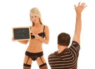 Izpoved študenta: »Imel sem razmerje s profesorico.« Sexy teacher in lingerie holds a chalk board with the title of the class -- "Sex 101". Eager male student sits at a red school desk with arm raised high, ready to participate in class!