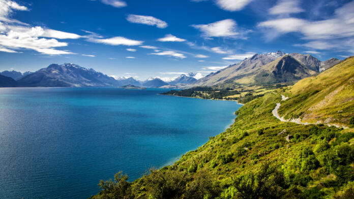 Summer view of Lake Wakatipu and the road from Queenstown to Glenorchy.  Southern Alps mountains in the distance.