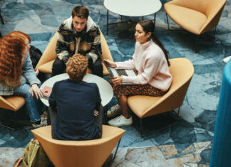 Pripravništvo v Sloveniji Teenagers at table working on project in college. Students in campus discussing on college presentation.