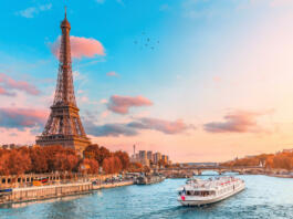The main attraction of Paris and all of Europe is the Eiffel tower in the rays of the setting sun on the bank of Seine river with cruise tourist ships