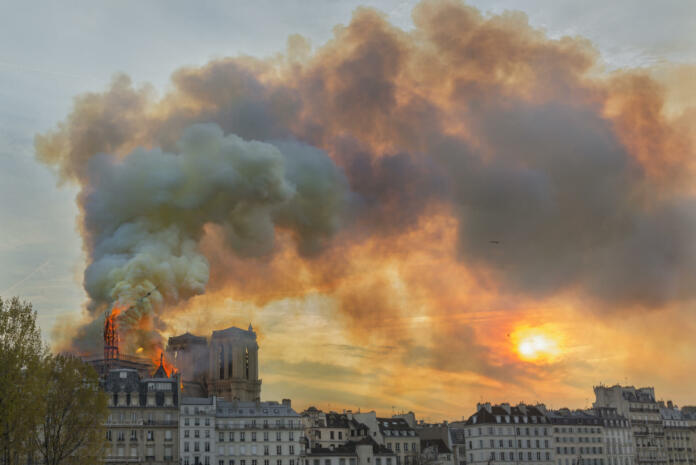 The spire on the back roof of Notre-Dame Cathedral burning and falling.