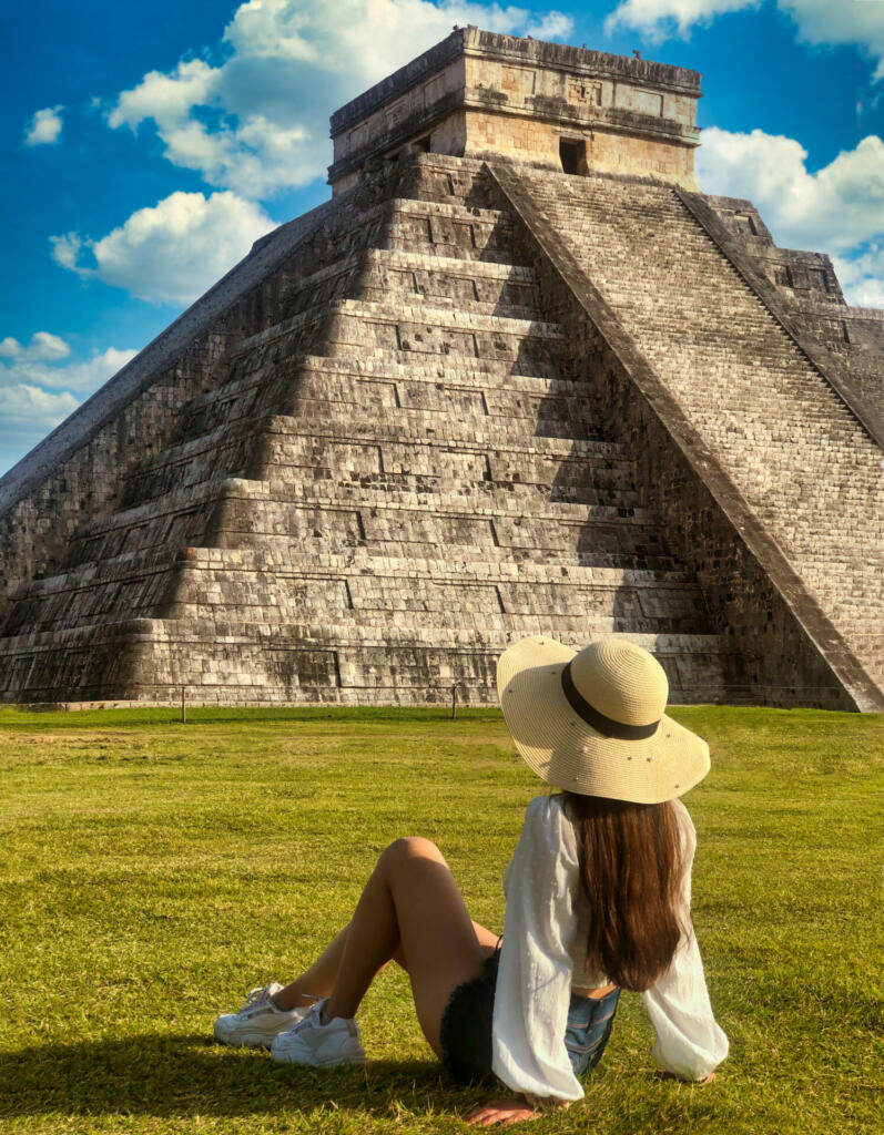Tourist woman sitting in front of the Chichen Itza pyramid in Yucatan, Mexico.