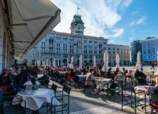Zanimivosti mesta Trst Trieste, Italy 16.10.2021: People enjoyin coffee at famous coffeeshop at the Piazza dell’Unità d’Italia, the main square in Trieste on sunny october day
