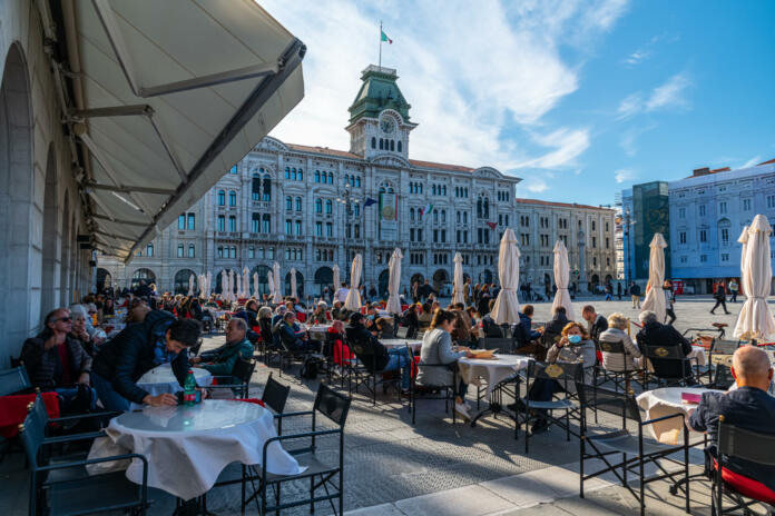 Trieste, Italy 16.10.2021: People enjoyin coffee at famous coffeeshop at the Piazza dell’Unità d’Italia, the main square in Trieste on sunny october day