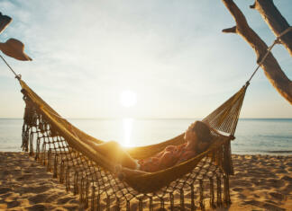 Bucket list: 10 stvari, ki jih moraš nujno narediti letošnje poletje Vacation Beach Summer Holiday Concept. Young woman relaxing in the hammock at sunset, island Phu Quoc, Vietnam.
