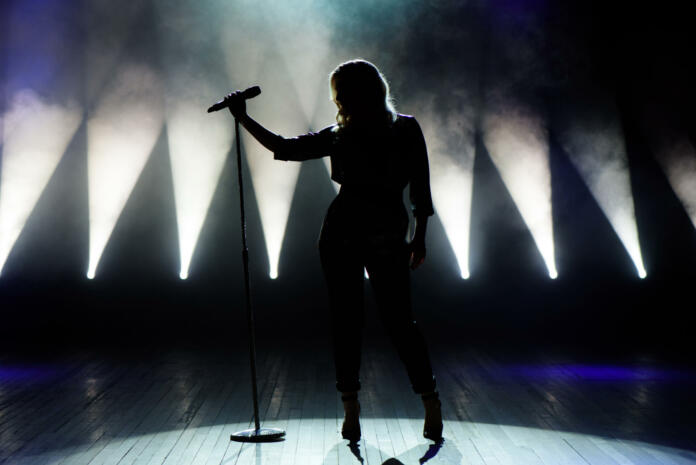 Vocalist singing to microphone. Singer in silhouette.