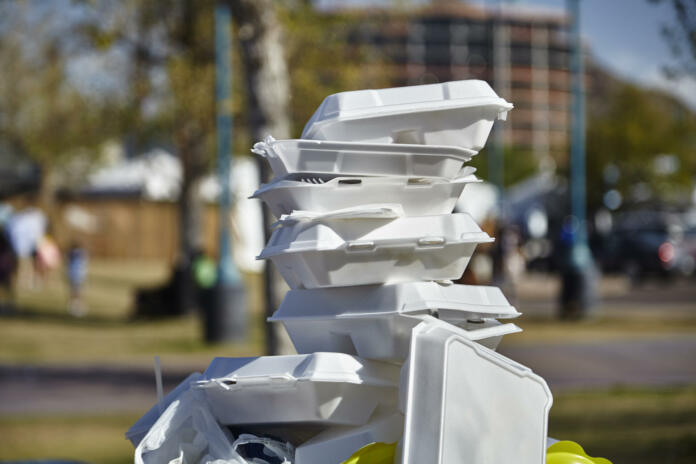 White styrofoam used food containers stacked in trash can in park