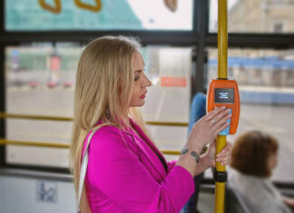 Dražja mesečna! Woman is using contactless payment terminal for payment of fares in city public transport. On the display of the device an inscription in Russian "it was paid, tariff 50 rubles".