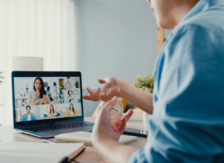 Za študente Univerze v Ljubljani brezplačne Zoom licence Young Asia businessman using laptop talk to colleagues about plan in video call meeting while work from home at living room. Self-isolation, social distancing, quarantine for corona virus prevention.