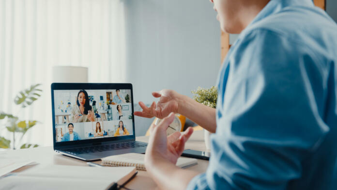 Young Asia businessman using laptop talk to colleagues about plan in video call meeting while work from home at living room. Self-isolation, social distancing, quarantine for corona virus prevention.