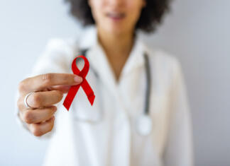 Prvi december – Svetovni dan boja proti aidsu AID, HIV red ribbon. Symbol of awareness, charity, support in disease, illness. Medical health care, help and hope. Sign of healthcare medicine campaign holding in female doctor.