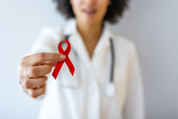 AID, HIV red ribbon. Symbol of awareness, charity, support in disease, illness. Medical health care, help and hope. Sign of healthcare medicine campaign holding in female doctor.
