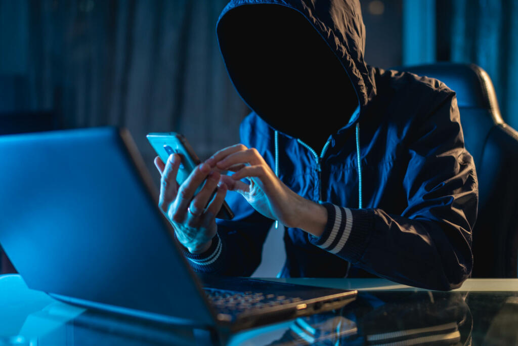 Anonymous hacker programmer uses a laptop to hack the system in the dark. Creation and infection of malicious virus. The concept of cybercrime and hacking database