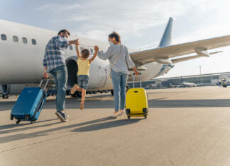 Kako bodo praznike preživeli znani Slovenci? Back view of parents holding the hands of the child and going with suitcases to board the plane