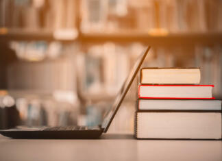 Vse, kar moraš vedeti o informativcih Bookshelves and laptops are placed on the library desk.E-learning class and e-book digital technology