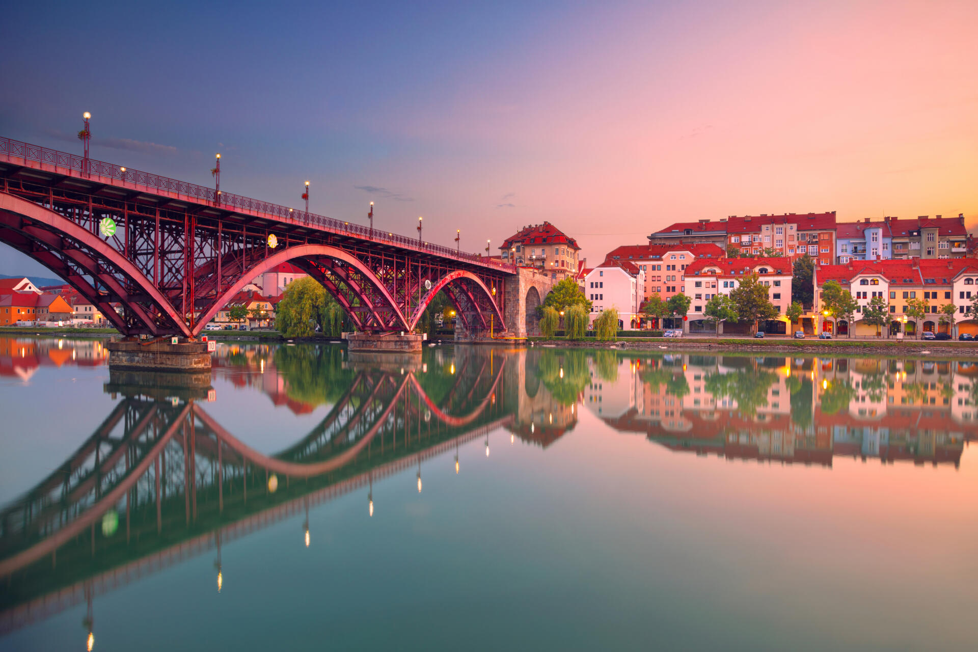 Cityscape image of Maribor, Slovenia at beautiful summer sunrise with reflection of the city in Drava River.