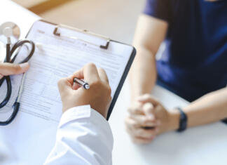 Sistematski zdravstveni pregledi študentov Close-up of a male doctor hand hold a silver pen and showing pad in hospital. Doctor giving prescription to the patient and filling up medical form at a clipboard